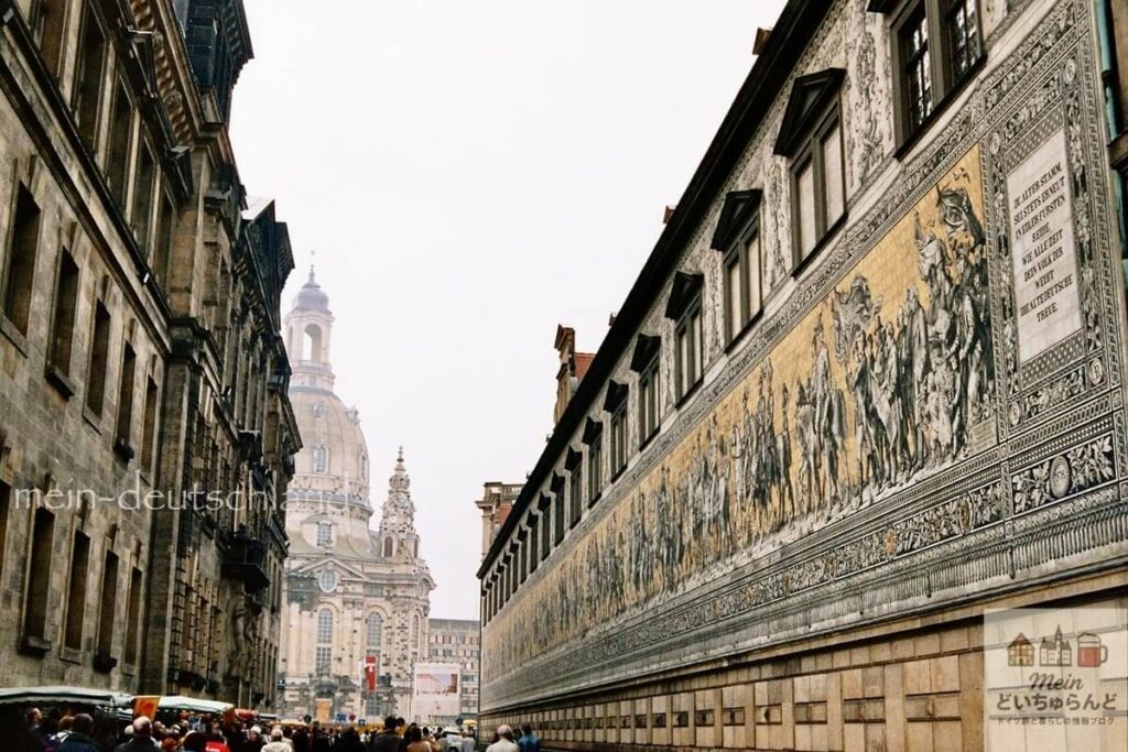 フュルステンツーク（君主の行列）の壁画と奥に見えるフラウエン教会