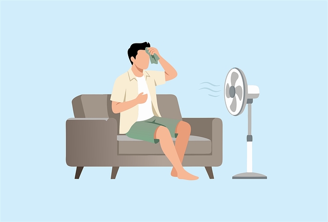 暑い日に扇風機に当たる男性